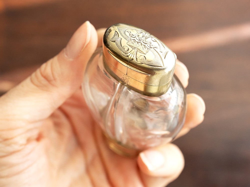A Victorian clear glass scent bottle with fluted sides and engraved sterling silver caps at the top and base. View VI