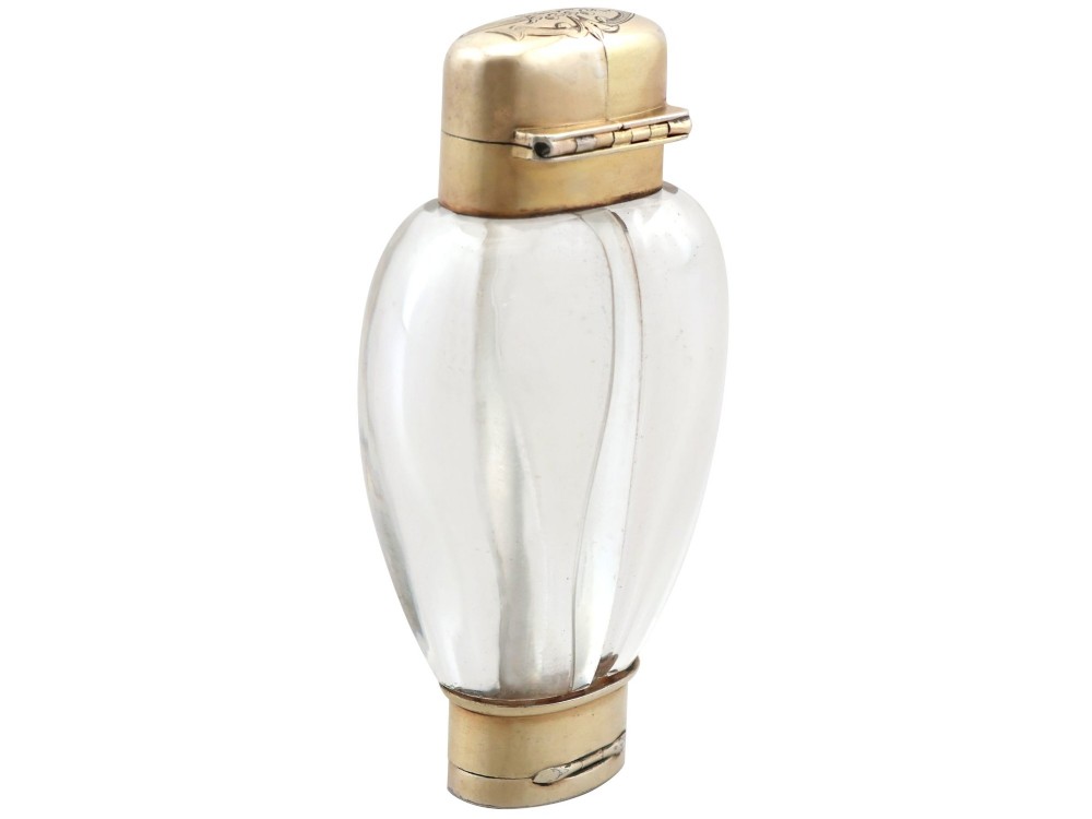 A Victorian clear glass scent bottle with fluted sides and engraved sterling silver caps at the top and base. View IX