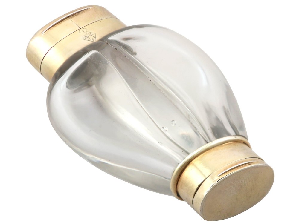 A Victorian clear glass scent bottle with fluted sides and engraved sterling silver caps at the top and base. View X