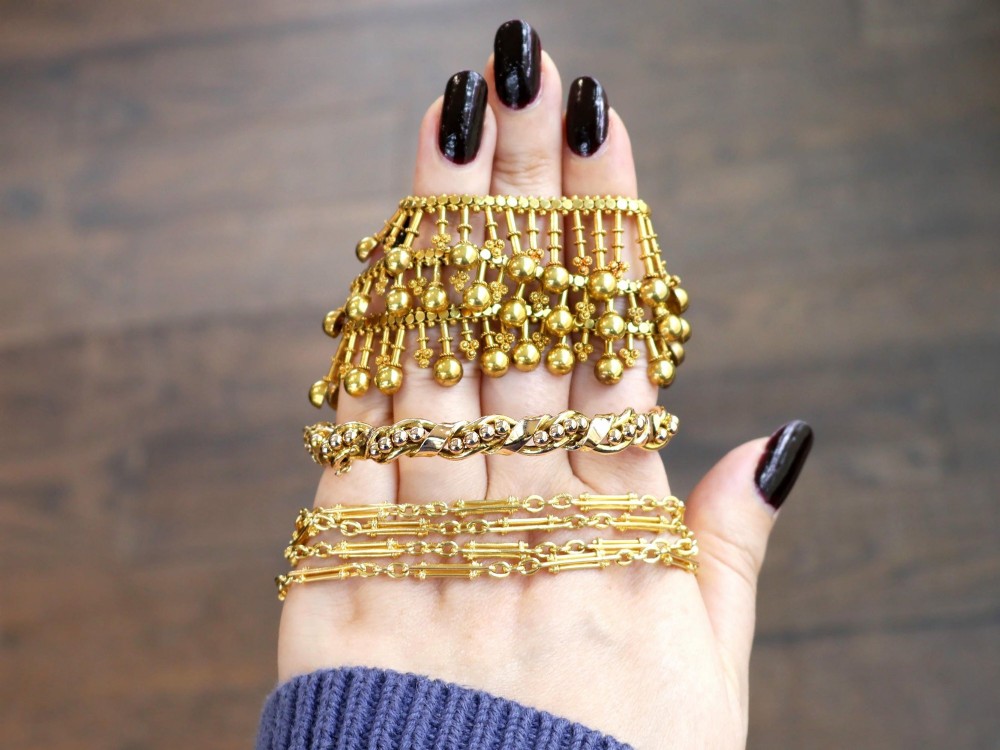 An antique Edwardian 15ct gold hinged bangle featuring a twisted ribbon design intertwined around a row of polished gold beads, fitted with a safety chain. View IV