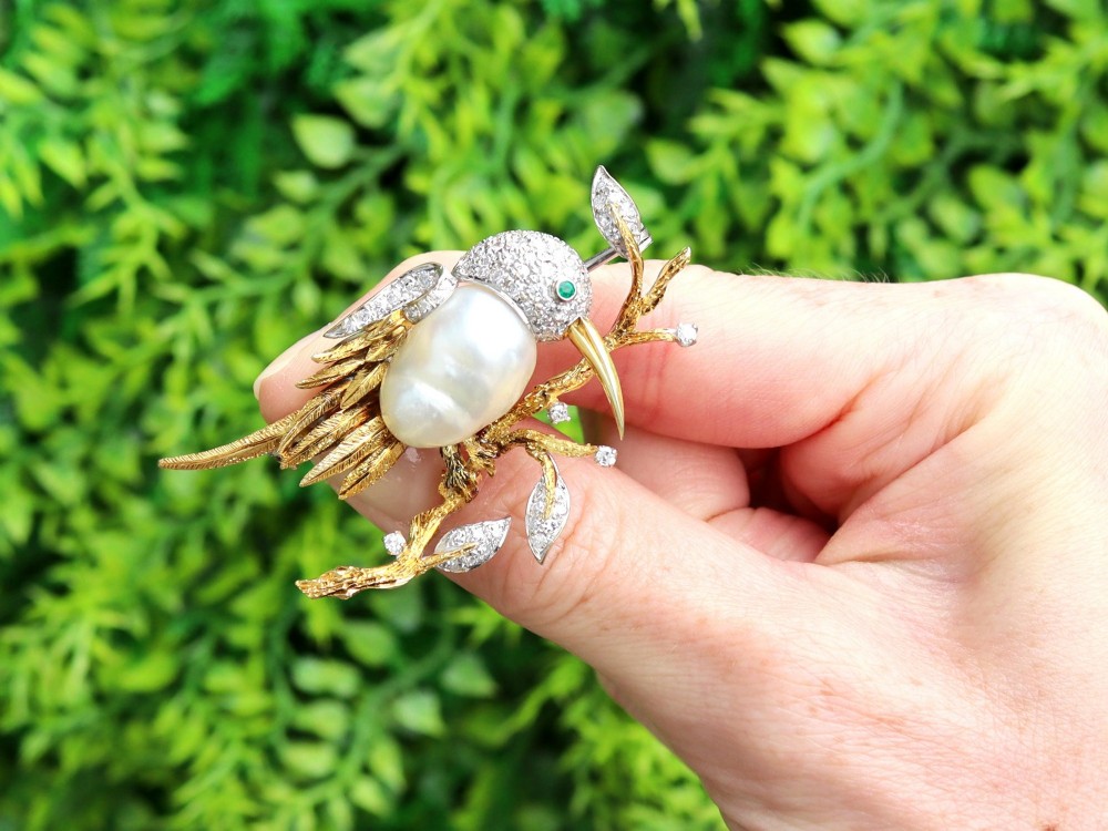 An antique 14ct gold bird brooch featuring a blister pearl body, pave diamond head with an emerald eye, perched on a textured gold branch. View II
