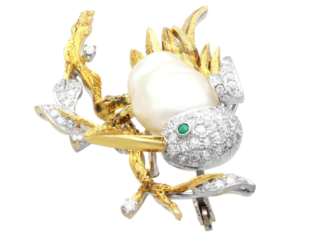 An antique 14ct gold bird brooch featuring a blister pearl body, pave diamond head with an emerald eye, perched on a textured gold branch. View VI