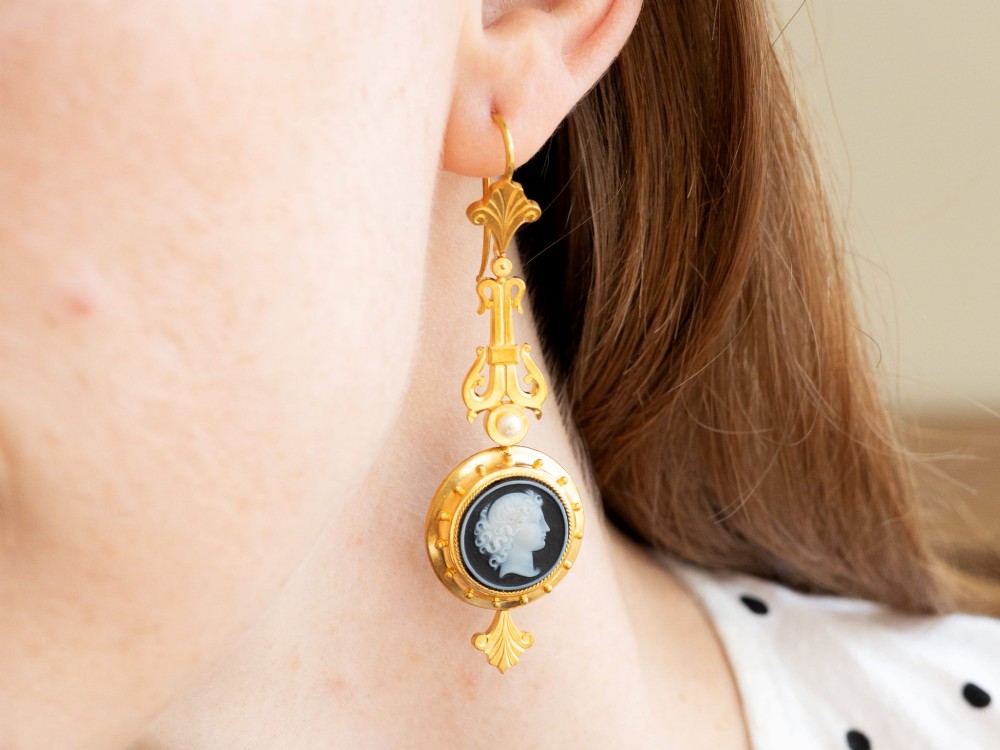 A pair of late Victorian 22ct yellow gold drop earrings featuring hand-carved hardstone cameo profile portraits and small seed pearls. View XIV