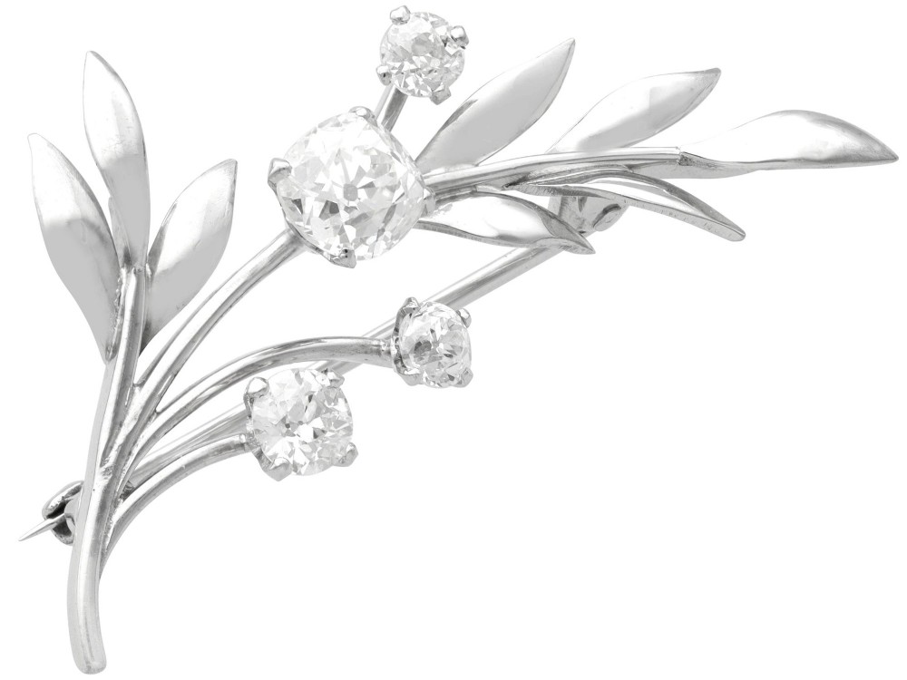 An 18ct white gold brooch crafted in the shape of a flowering spray, featuring leaf motifs and claw-set diamonds.