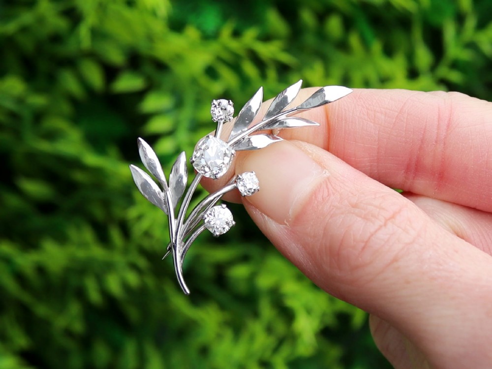 An 18ct white gold brooch crafted in the shape of a flowering spray, featuring leaf motifs and claw-set diamonds. View II