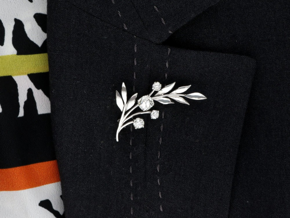 An 18ct white gold brooch crafted in the shape of a flowering spray, featuring leaf motifs and claw-set diamonds. View IX
