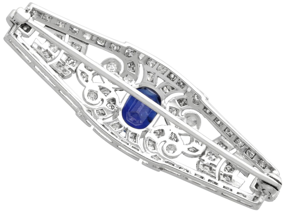 An Art Deco 9ct white gold brooch featuring a central oval blue sapphire framed by geometric openwork set with round diamonds. View VII