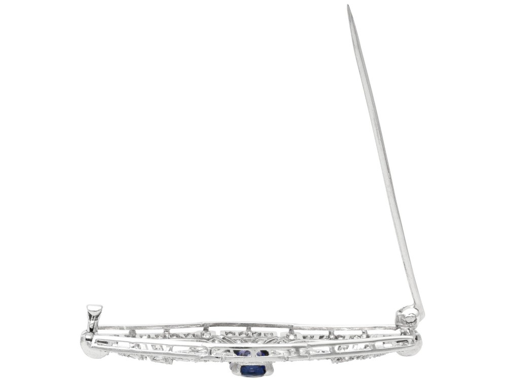 An Art Deco 9ct white gold brooch featuring a central oval blue sapphire framed by geometric openwork set with round diamonds. View VIII
