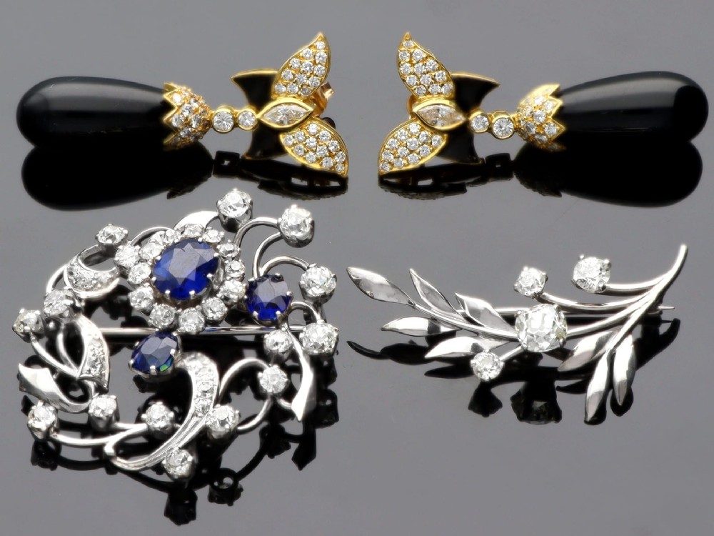 An Edwardian 18ct white gold brooch set with three oval blue sapphires surrounded by openwork diamond-set scrollwork. View IV
