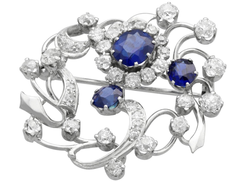 An Edwardian 18ct white gold brooch set with three oval blue sapphires surrounded by openwork diamond-set scrollwork. View VI