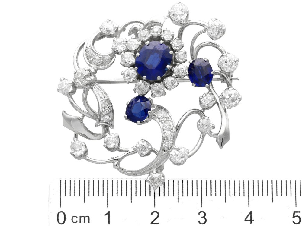 An Edwardian 18ct white gold brooch set with three oval blue sapphires surrounded by openwork diamond-set scrollwork. View IX