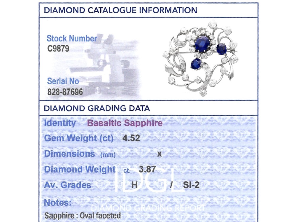 An Edwardian 18ct white gold brooch set with three oval blue sapphires surrounded by openwork diamond-set scrollwork. View XI