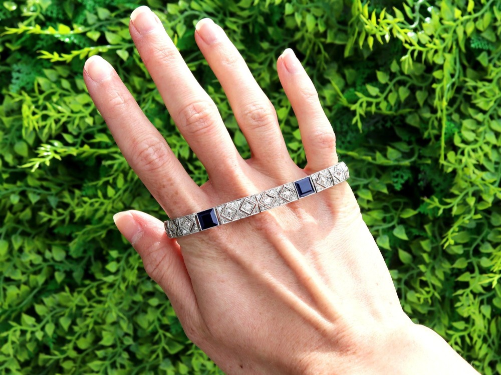 An Art Deco platinum bracelet featuring square basaltic blue sapphires and diamond-shaped link panels set with old-cut diamonds. View II