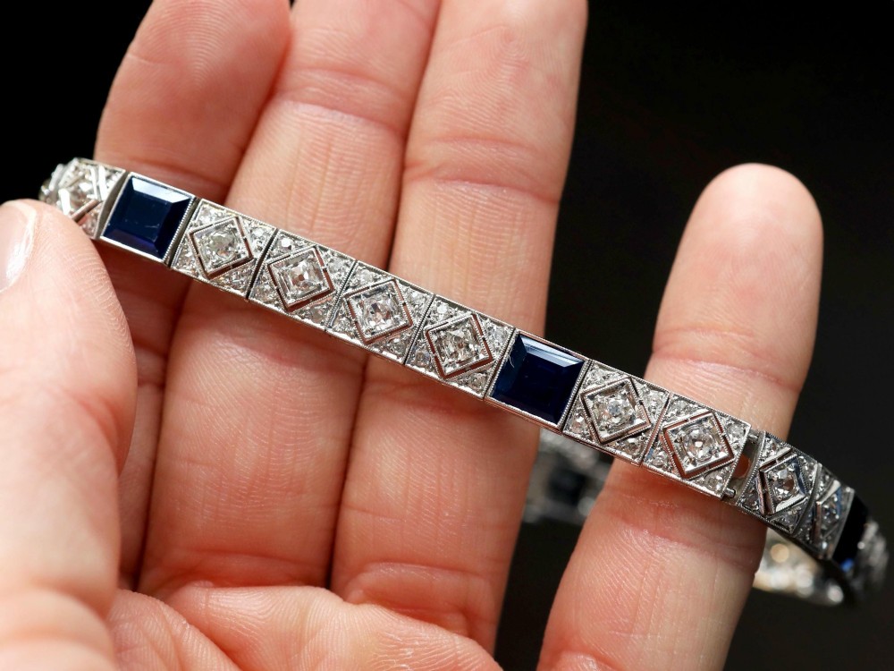 An Art Deco platinum bracelet featuring square basaltic blue sapphires and diamond-shaped link panels set with old-cut diamonds. View IV