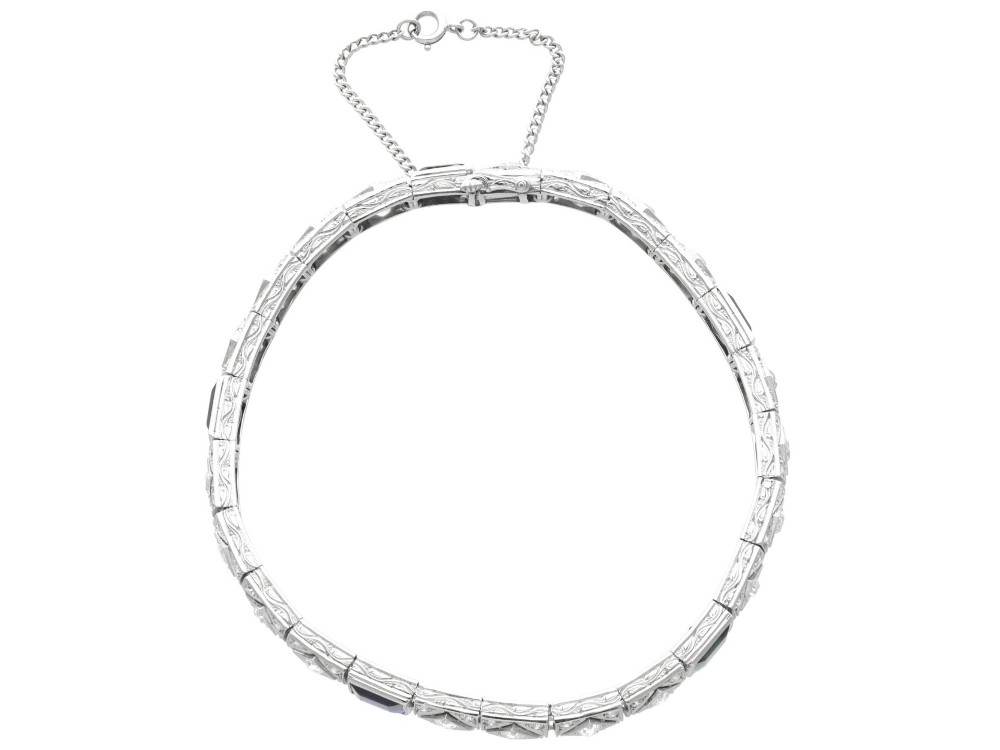 An Art Deco platinum bracelet featuring square basaltic blue sapphires and diamond-shaped link panels set with old-cut diamonds. View VI