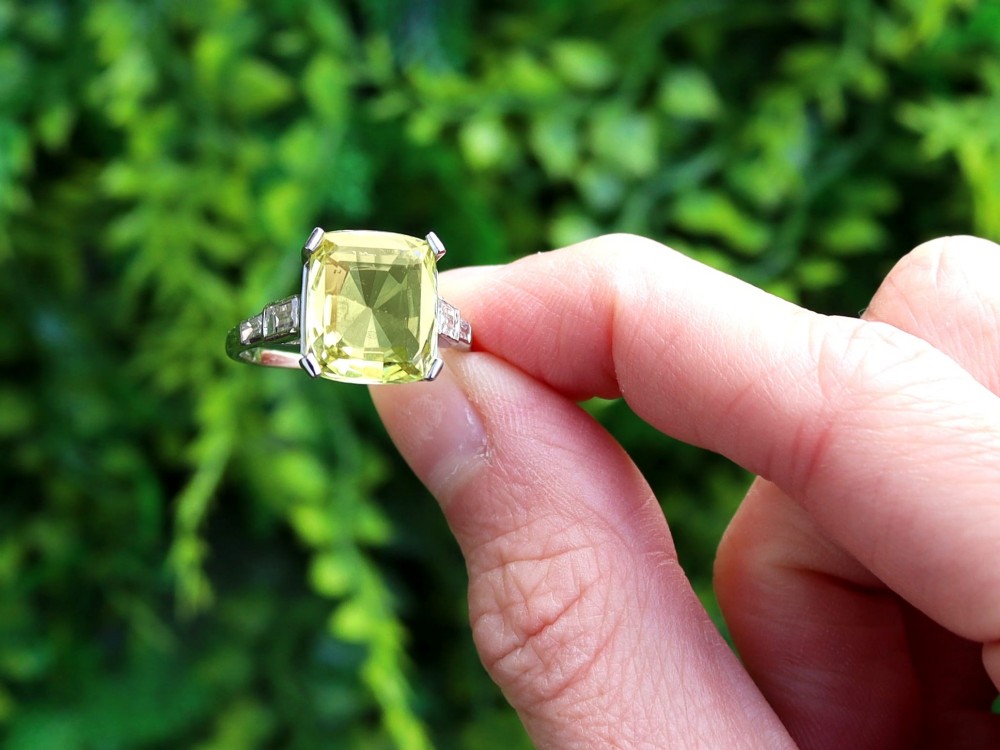 An Art Deco platinum ring featuring a large cushion cut yellow chrysoberyl central gemstone flanked by step cut diamonds on the shoulders. View II