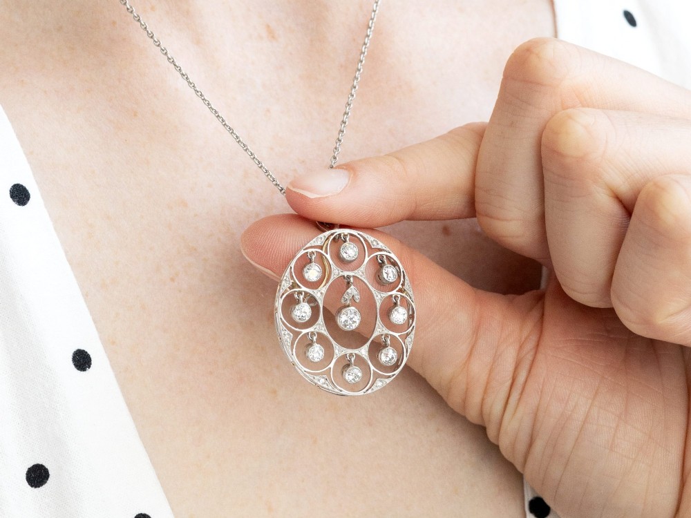 An Art Deco circular platinum pendant featuring openwork wirework circles set with diamonds, suspended from a fine chain. View III