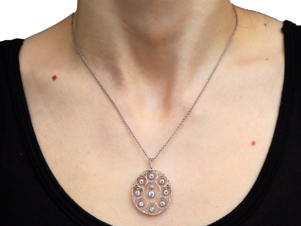 An Art Deco circular platinum pendant featuring openwork wirework circles set with diamonds, suspended from a fine chain. View IX