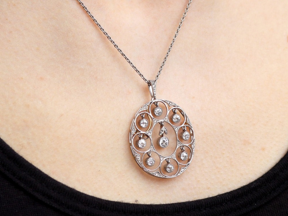 An Art Deco circular platinum pendant featuring openwork wirework circles set with diamonds, suspended from a fine chain. View X