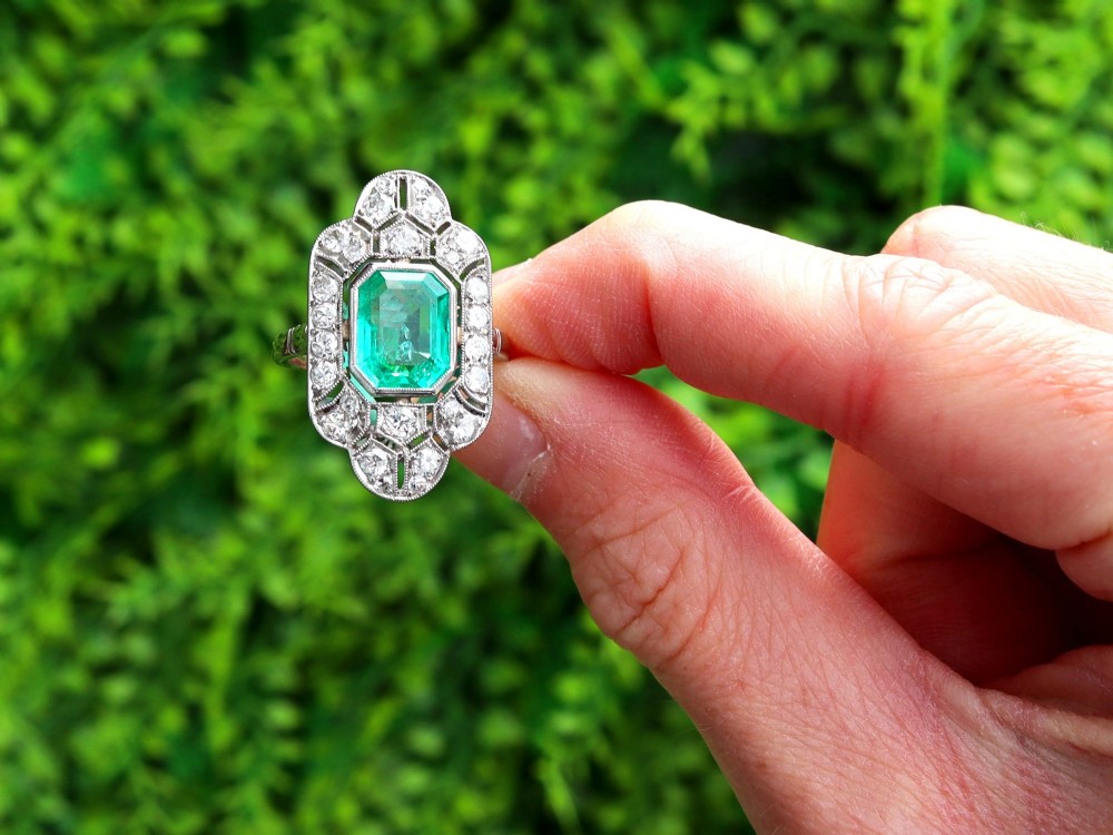 An Art Deco platinum dress ring featuring a central rectangular emerald surrounded by an elongated geometric pierced frame set with diamonds. View II