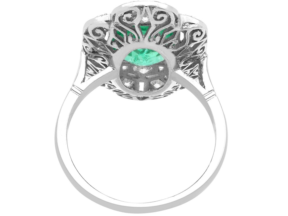 An Art Deco platinum dress ring featuring a central rectangular emerald surrounded by an elongated geometric pierced frame set with diamonds. View VIII