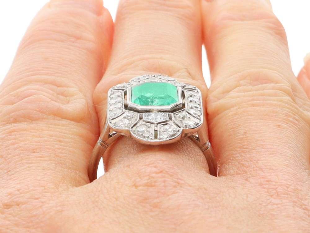 An Art Deco platinum dress ring featuring a central rectangular emerald surrounded by an elongated geometric pierced frame set with diamonds. View XI