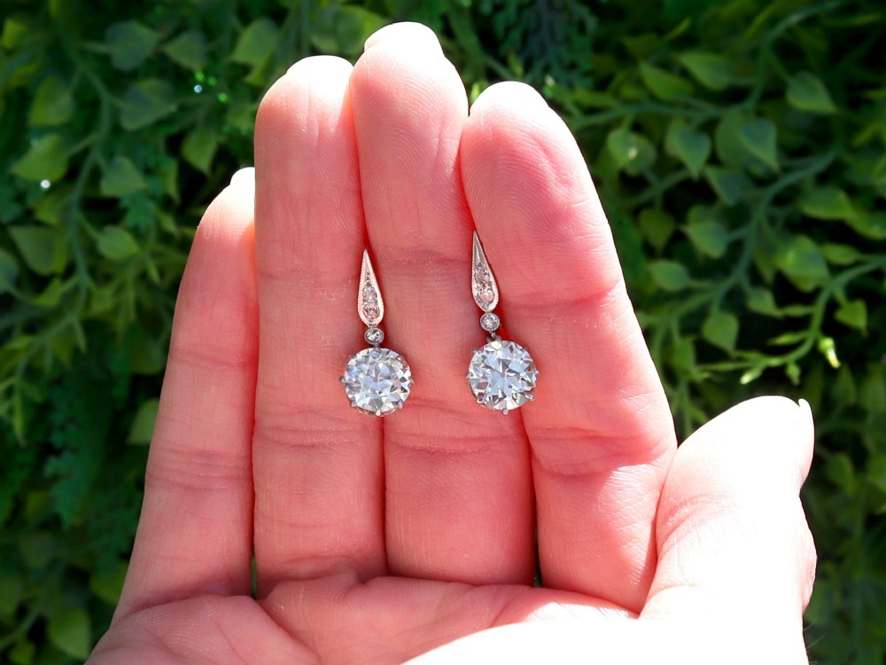 A pair of antique diamond drop earrings featuring round diamonds suspended from decorative articulated mounts. View II