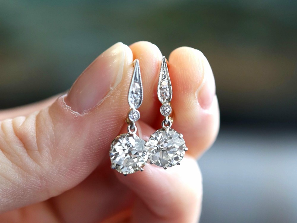 A pair of antique diamond drop earrings featuring round diamonds suspended from decorative articulated mounts. View III
