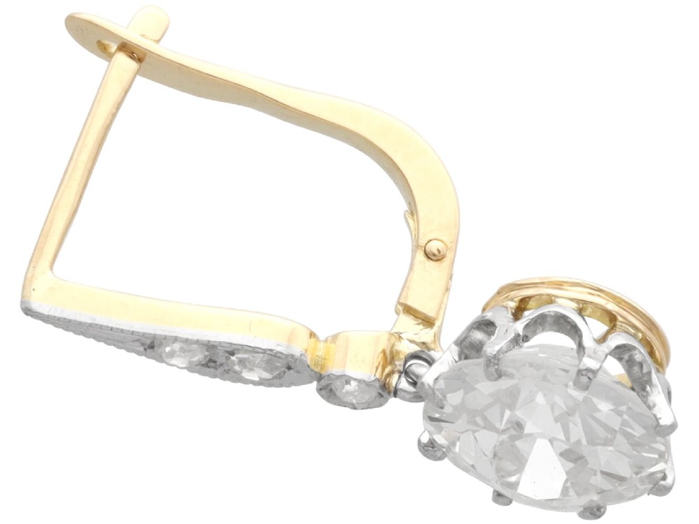 A pair of antique diamond drop earrings featuring round diamonds suspended from decorative articulated mounts. View V