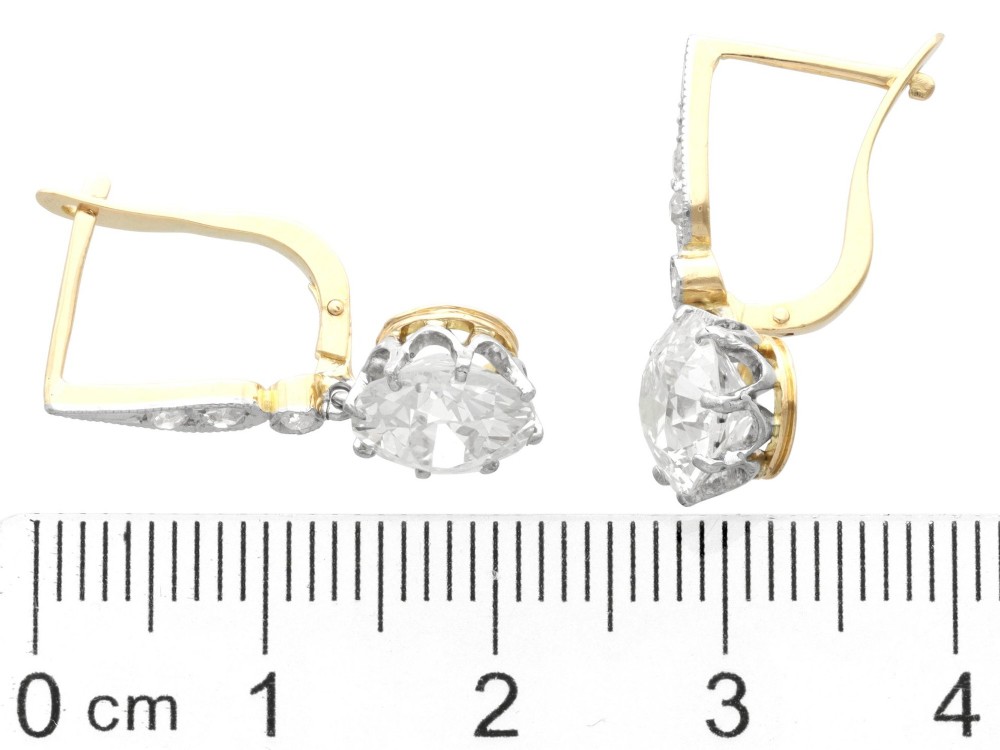 A pair of antique diamond drop earrings featuring round diamonds suspended from decorative articulated mounts. View VII