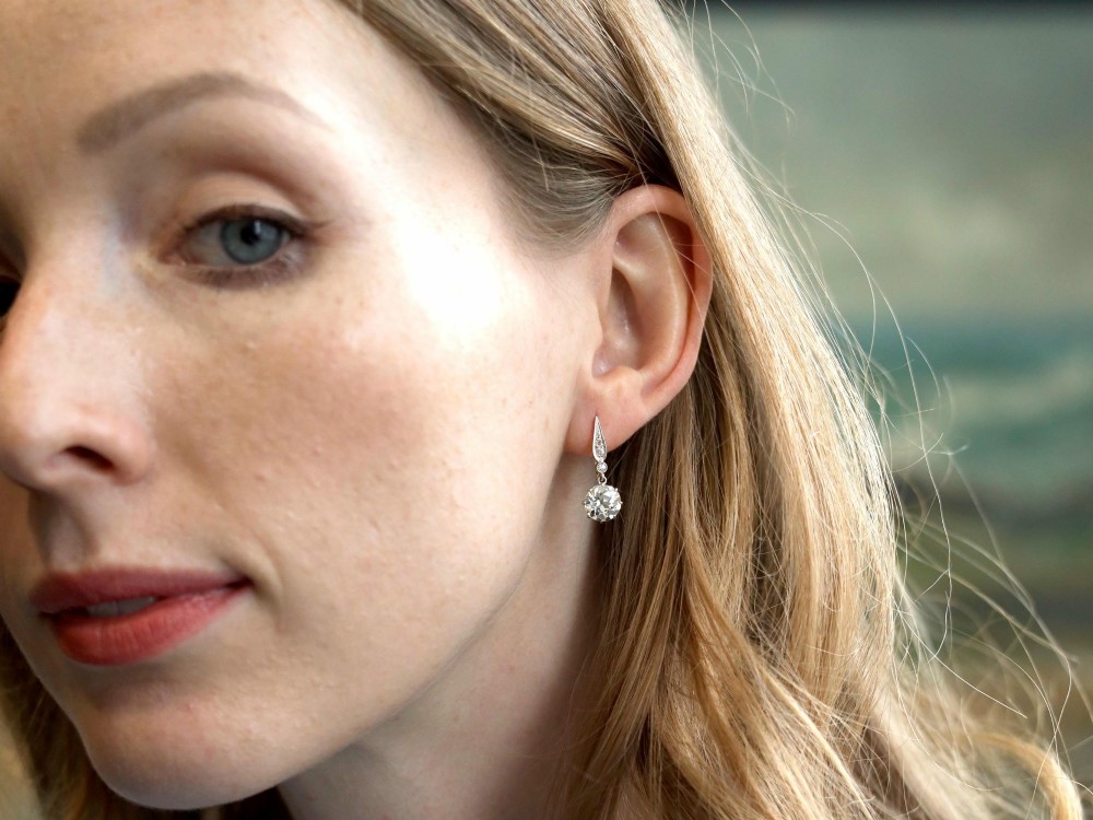 A pair of antique diamond drop earrings featuring round diamonds suspended from decorative articulated mounts. View VIII