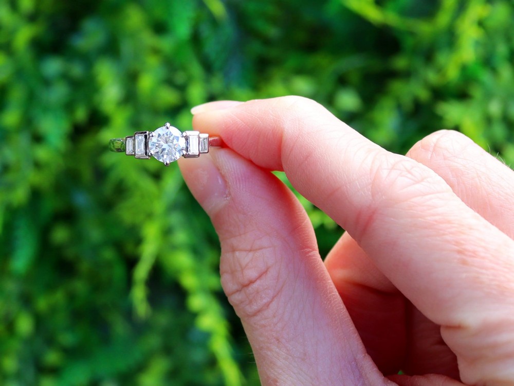 An 18ct white gold Art Deco ring featuring a central round diamond flanked by stepped baguette diamond shoulders. View II