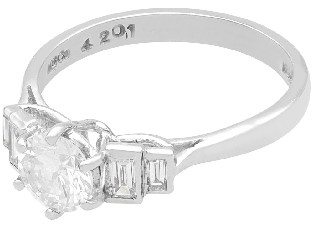 An 18ct white gold Art Deco ring featuring a central round diamond flanked by stepped baguette diamond shoulders. View IV