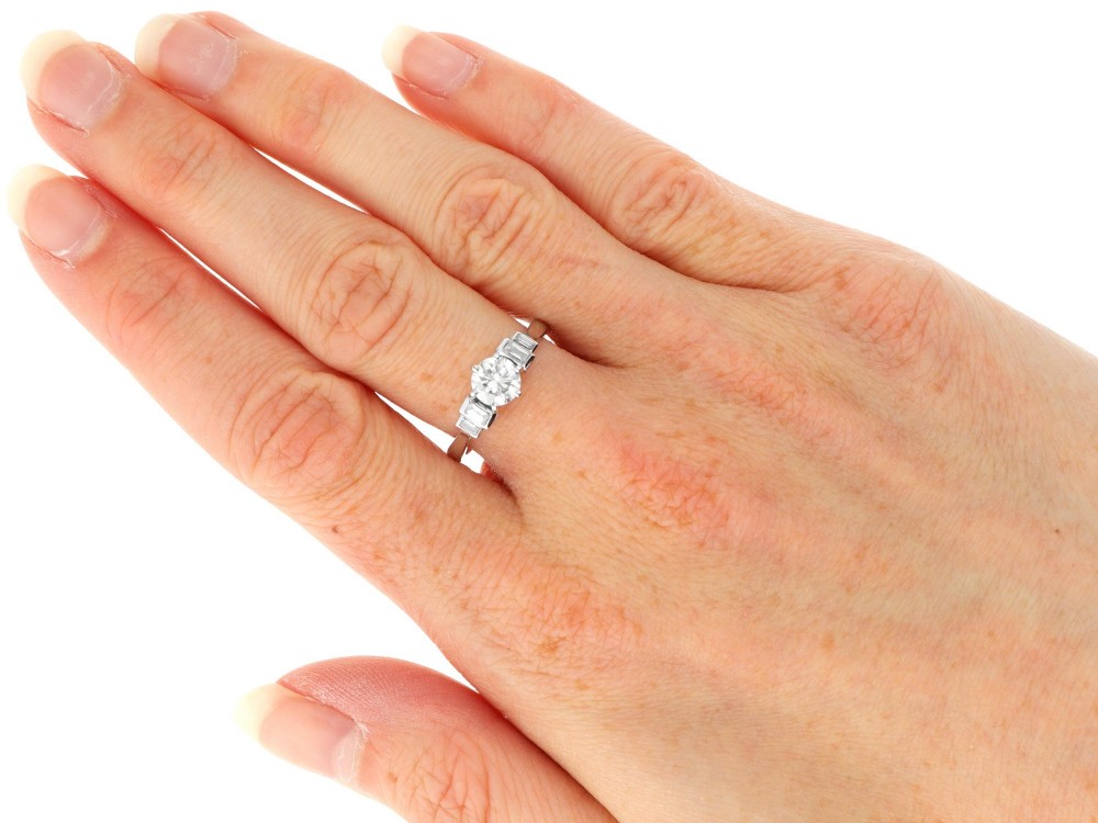 An 18ct white gold Art Deco ring featuring a central round diamond flanked by stepped baguette diamond shoulders. View VII
