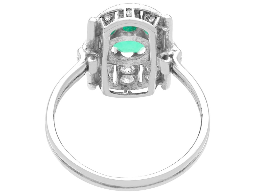 An Art Deco 14ct white gold ring featuring a central round green emerald framed by geometric shoulders set with small brilliant diamonds. View V