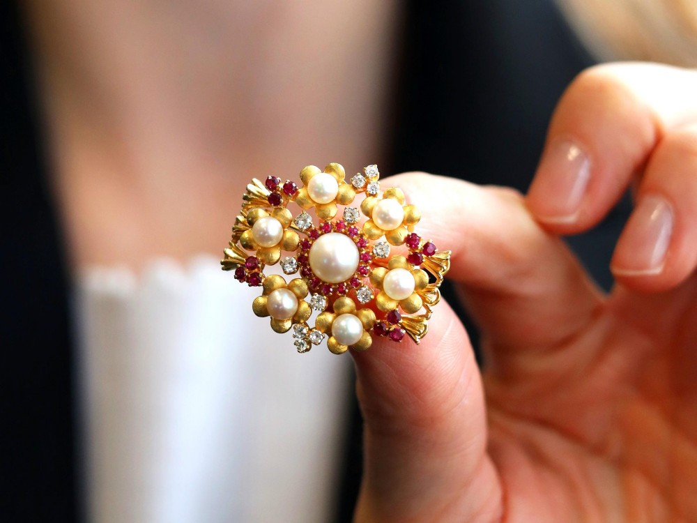 An 18ct yellow gold floral cluster brooch set with a central pearl surrounded by small rubies, outer cultured pearls, round diamonds, and red rubies. View III
