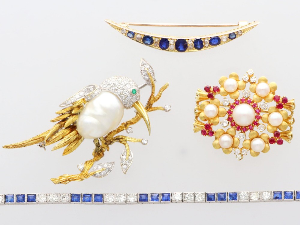 An 18ct yellow gold floral cluster brooch set with a central pearl surrounded by small rubies, outer cultured pearls, round diamonds, and red rubies. View VI