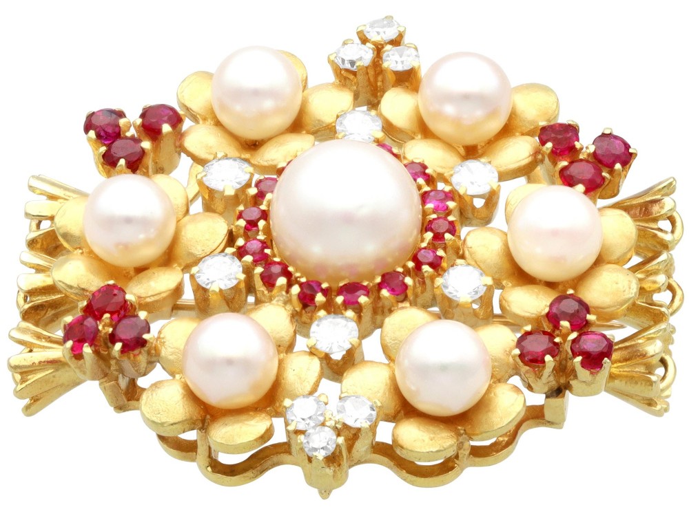 An 18ct yellow gold floral cluster brooch set with a central pearl surrounded by small rubies, outer cultured pearls, round diamonds, and red rubies. View IX