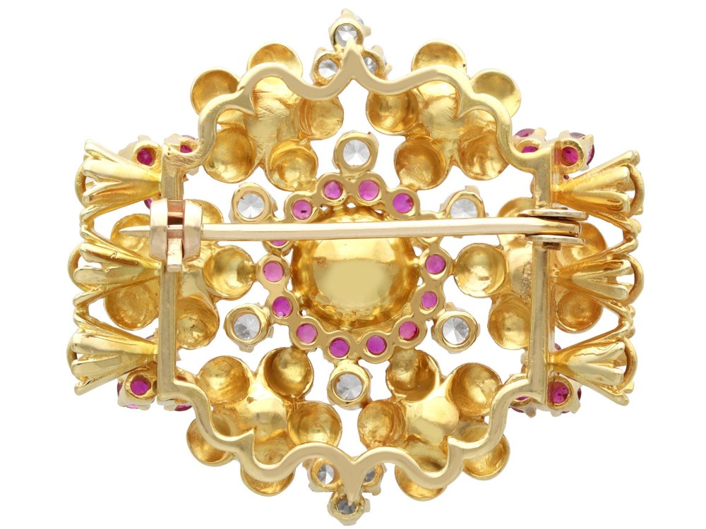 An 18ct yellow gold floral cluster brooch set with a central pearl surrounded by small rubies, outer cultured pearls, round diamonds, and red rubies. View X