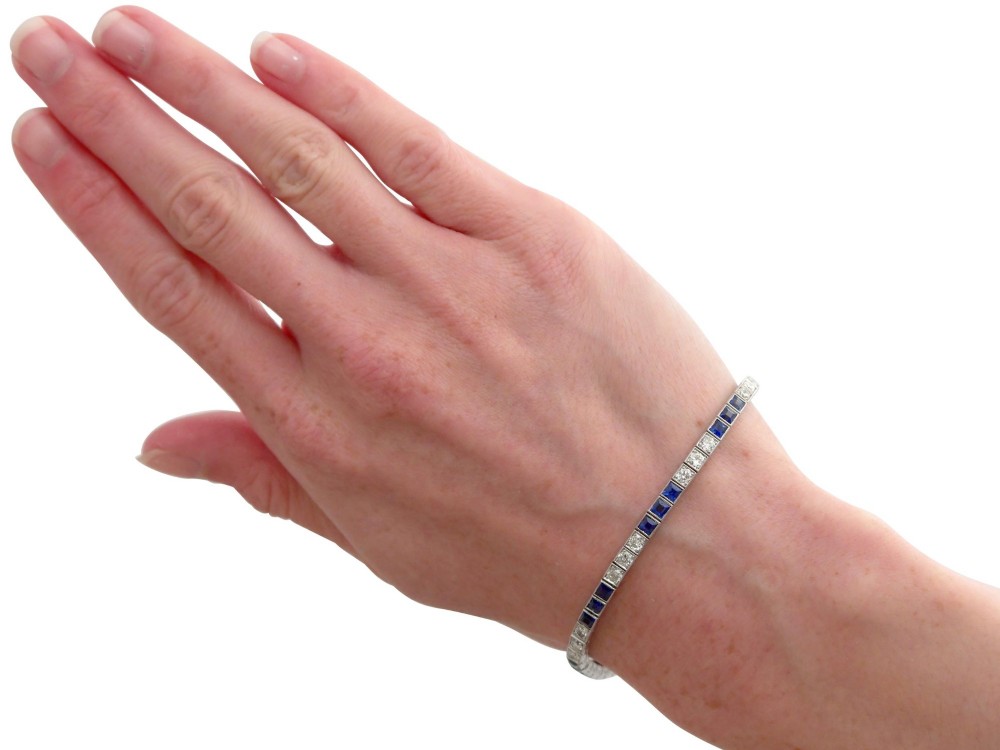 An Art Deco platinum line bracelet set with alternating square blue sapphires and round brilliant diamonds. View XIV