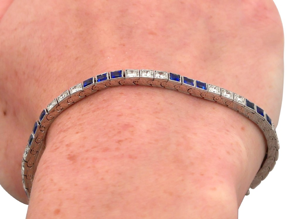 An Art Deco platinum line bracelet set with alternating square blue sapphires and round brilliant diamonds. View XV