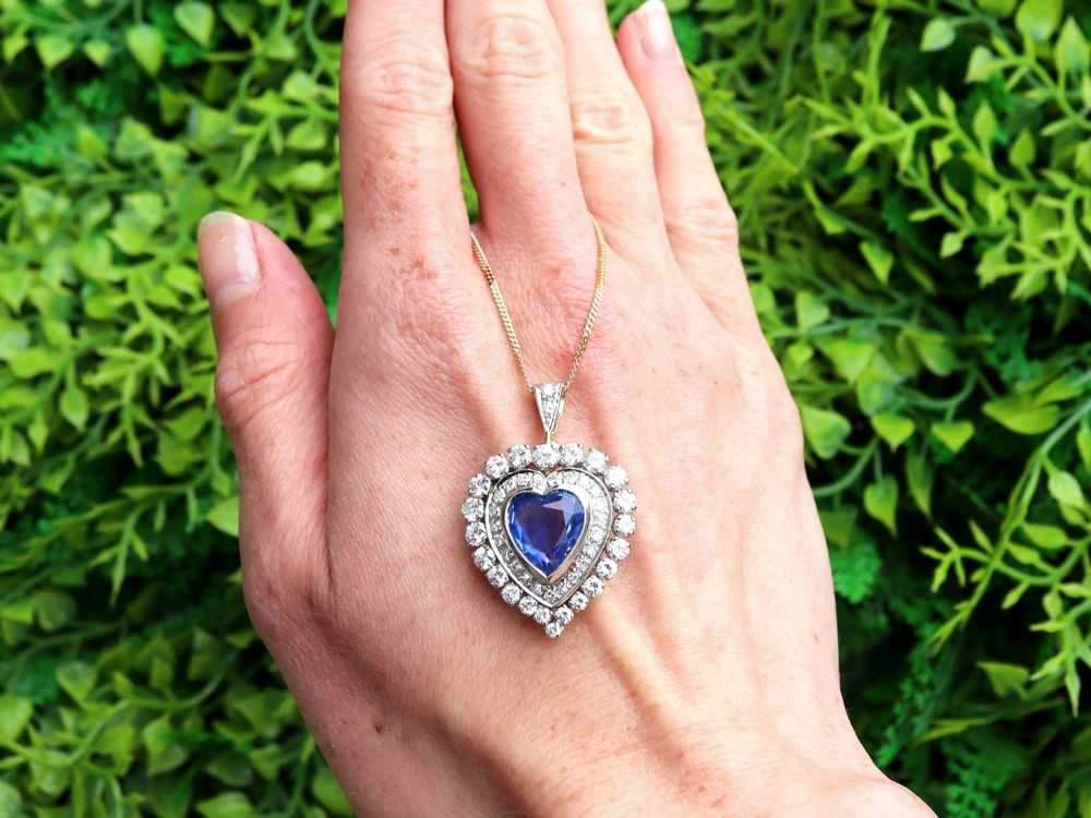 A heart-shaped 14ct yellow gold pendant featuring a central heart-cut Ceylon sapphire surrounded by a double halo of brilliant-cut diamonds. View II