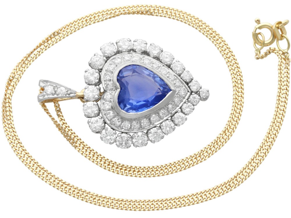 A heart-shaped 14ct yellow gold pendant featuring a central heart-cut Ceylon sapphire surrounded by a double halo of brilliant-cut diamonds. View V