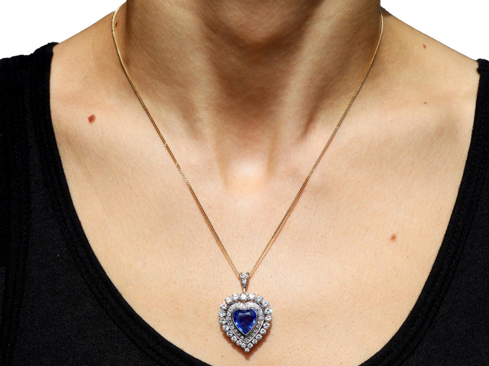 A heart-shaped 14ct yellow gold pendant featuring a central heart-cut Ceylon sapphire surrounded by a double halo of brilliant-cut diamonds. View IX
