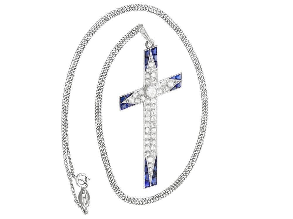 An antique Edwardian cross pendant set with diamonds and geometric blue sapphires suspended from a chain. View VI
