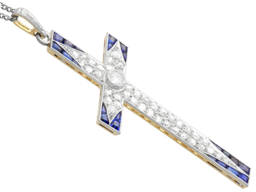 An antique Edwardian cross pendant set with diamonds and geometric blue sapphires suspended from a chain. View VII