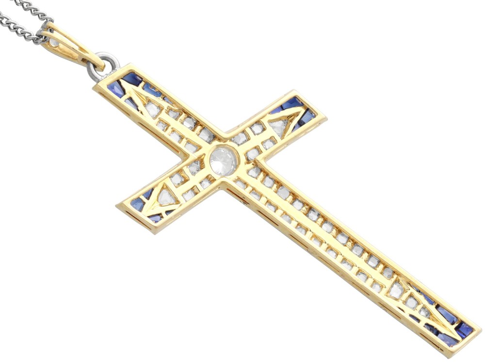 An antique Edwardian cross pendant set with diamonds and geometric blue sapphires suspended from a chain. View VIII