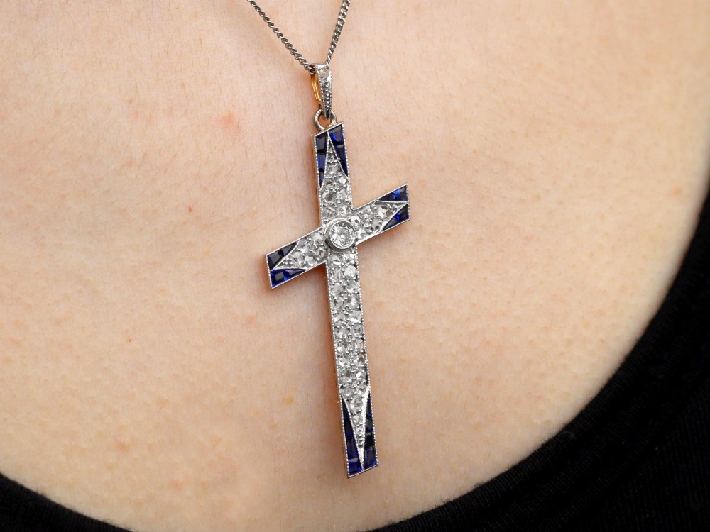 An antique Edwardian cross pendant set with diamonds and geometric blue sapphires suspended from a chain. View XI