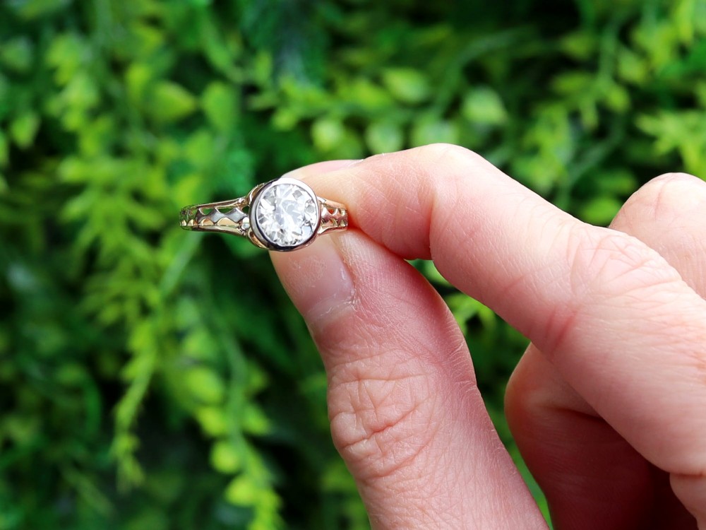 An antique 15ct yellow gold solitaire ring featuring a bezel-set round diamond with decorative openwork shoulders. View II