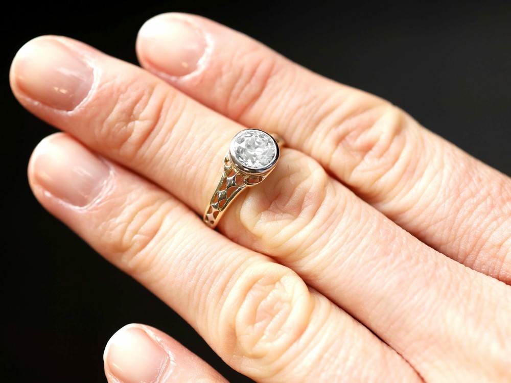 An antique 15ct yellow gold solitaire ring featuring a bezel-set round diamond with decorative openwork shoulders. View III